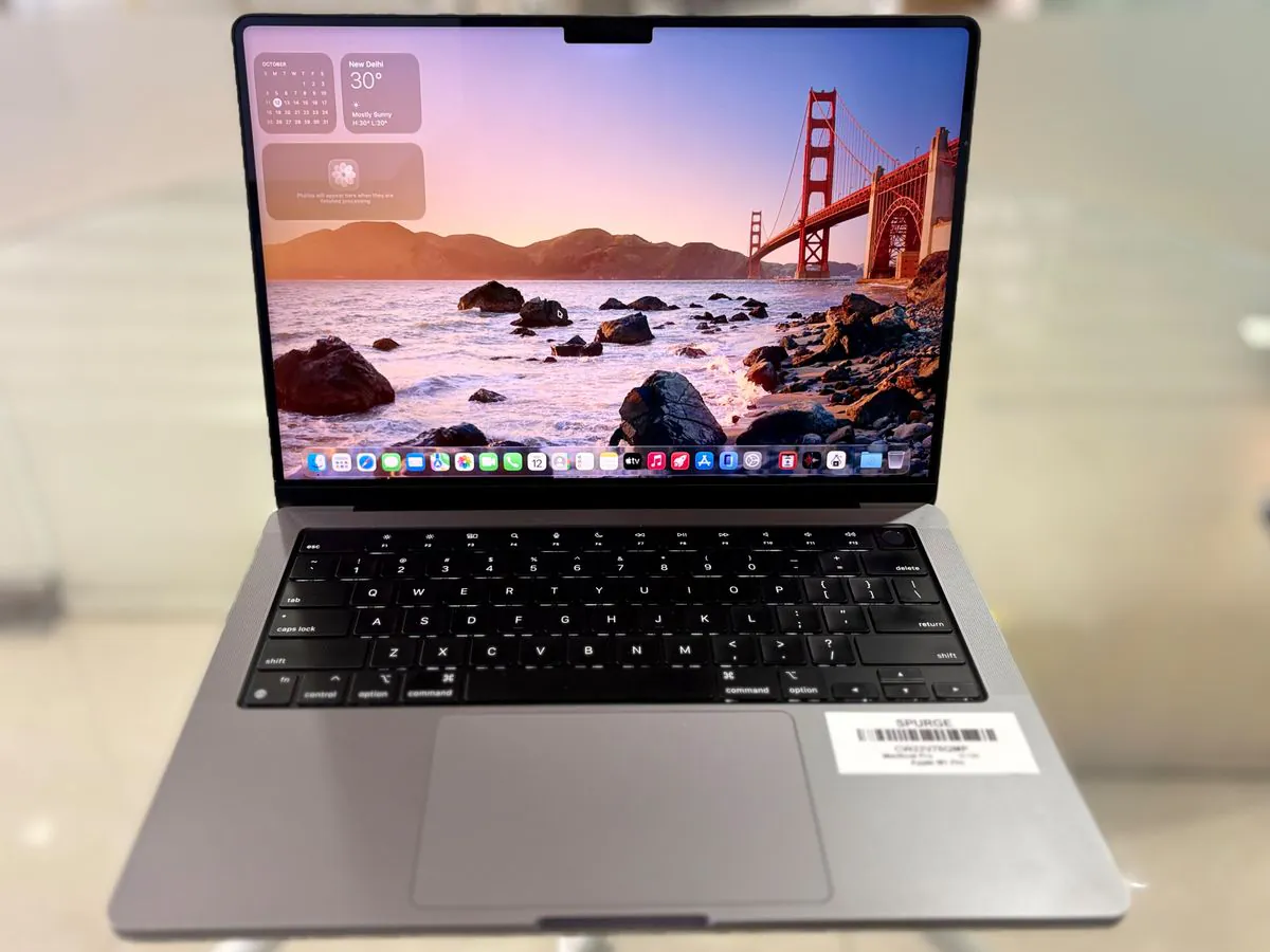 MacBook Pro 14-inch M1 Pro in Silver, open facing the camera, showing the Liquid Retina XDR display, keyboard, trackpad and Touch ID key with a SPURGE asset label on the palm rest