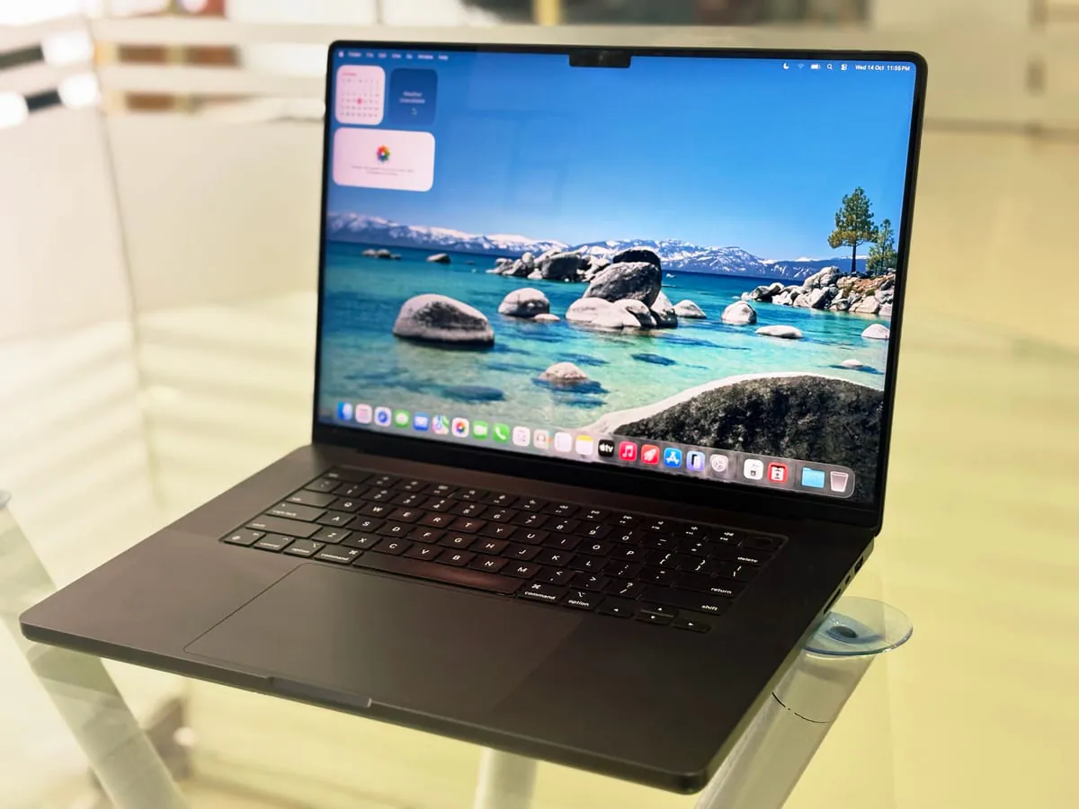 MacBook Pro 16-inch M3 Max from a closer left three-quarter angle with the display on, showing the keyboard, trackpad and Touch ID key
