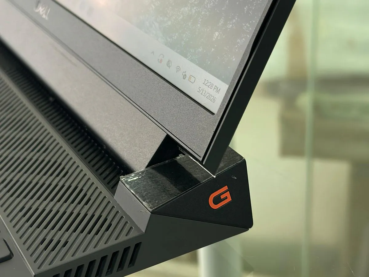 Close-up of the Dell G15 5530 rear hinge with the orange G logo and side vent grilles