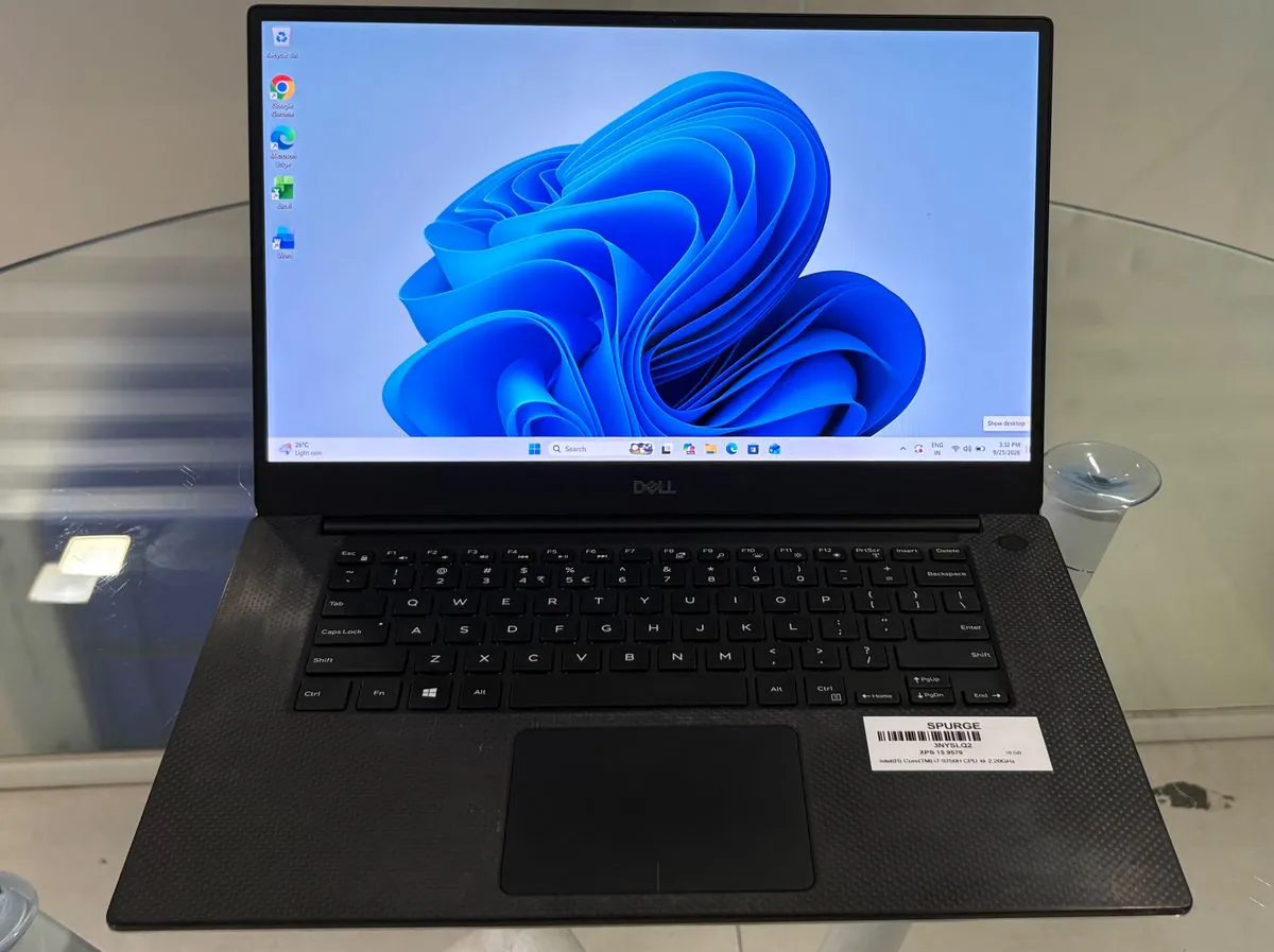 Dell XPS 15 9570, open facing the camera with the Windows desktop on, showing the narrow-bezel 15.6-inch display, backlit keyboard, carbon-fibre palm rest and large trackpad