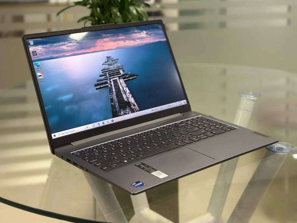 Lenovo IdeaPad Slim 3i 15IRH8 from the left showing the Arctic grey deck, keyboard, touchpad, palm-rest Intel Core i7 sticker and left-side ports with the display on