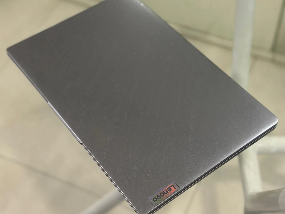 Closed Arctic grey Lenovo IdeaPad Slim 3i lid photographed from above on a glass table