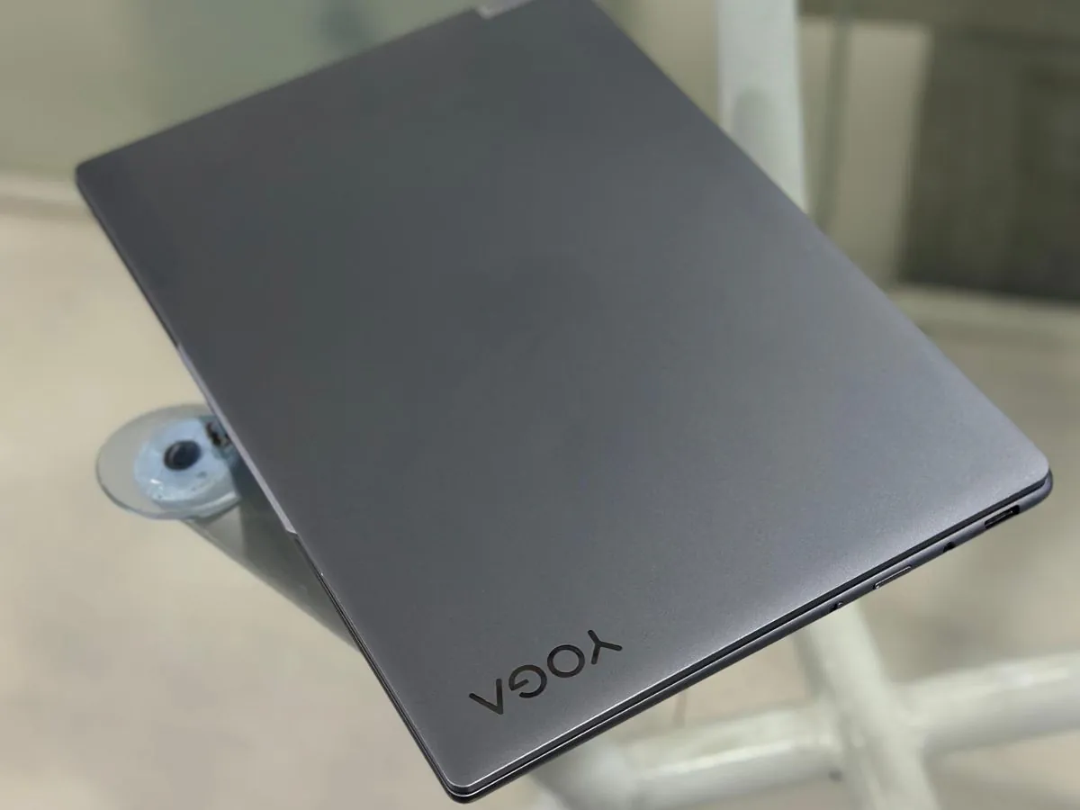 Closed Luna grey Lenovo Yoga Slim 7 lid with YOGA logo photographed from above on a glass table