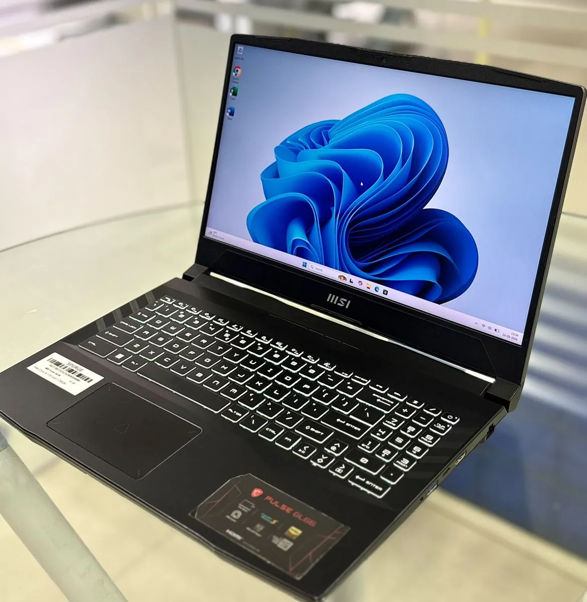 MSI Pulse GL66 open from a left three-quarter angle, showing the display on, backlit keyboard with numeric keypad, and touchpad